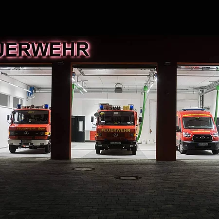 FFW Gädheim-Ottendorf Einfahrt der Feuerwehrwache mit offenen Toren und geparkten Feuerwehreinsatzwagen.